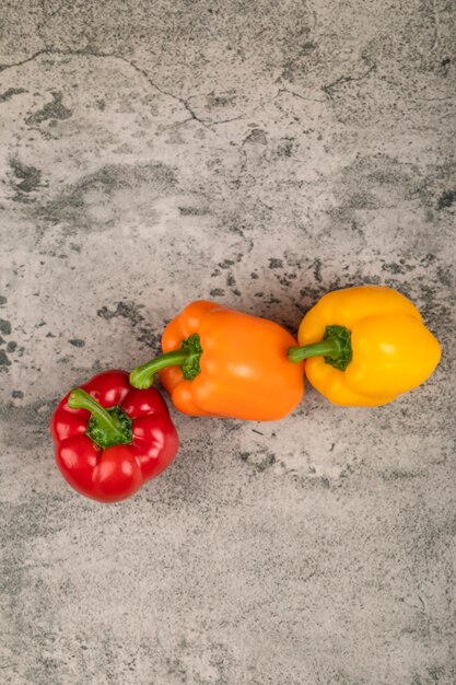 Sweet colorful bell peppers placed on stone surface