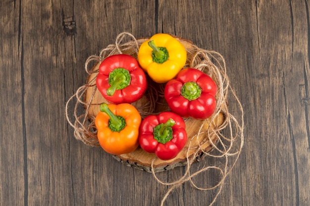 Sweet colorful bell peppers placed on wood piece