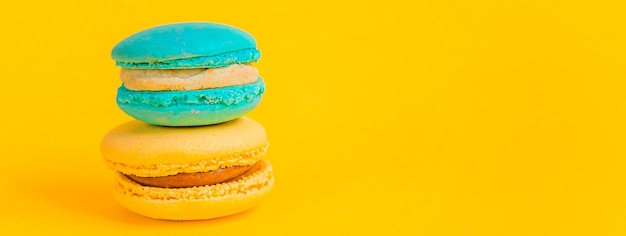 Sweet colorful blue yellow macaron dessert cake isolated on yellow background