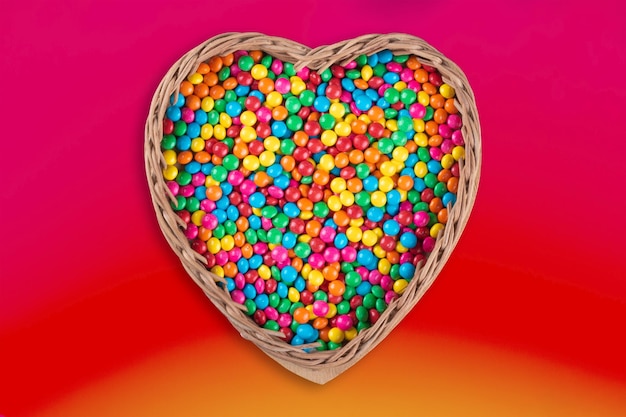 Сладкие красочные конфетти в корзине сердца с розово-красным градиентным фоном