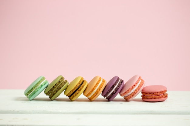 Maccheroni o macaron francesi dolci e colourful sul fondo di legno bianco di rosa della tavola, dessert.