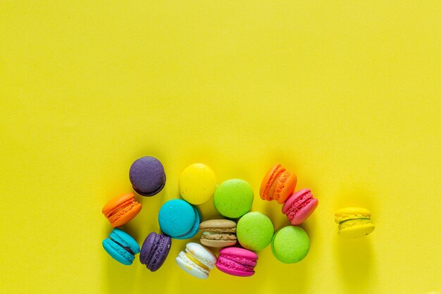 Sweet and colorful french macaroons or macaroon on yellow background Dessert eating with tea or cof