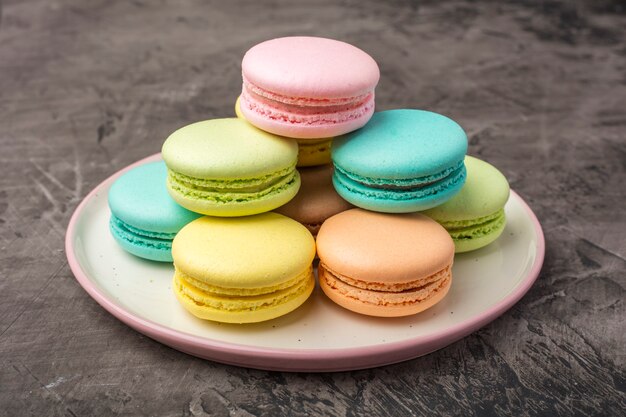 Sweet colorful macarons on the plate Dark background