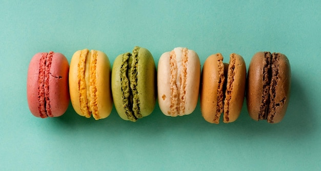 Sweet colorful macarons in a row on a turquoise background