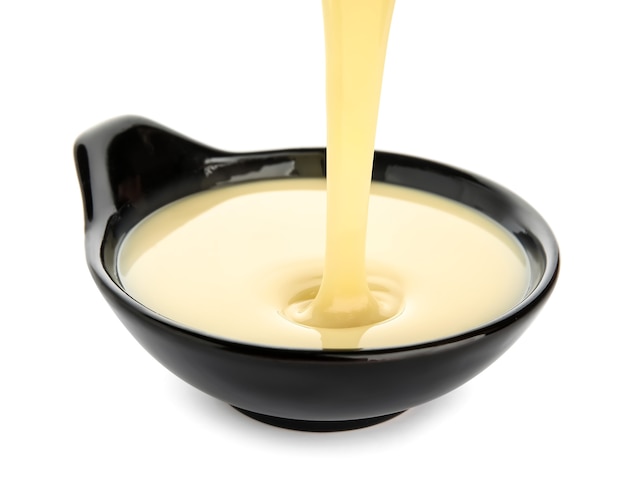 Sweet condensed milk pouring into bowl