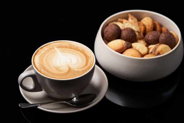 Сладкая закуска печенья и чашка кофе капучино на столе, крупный план