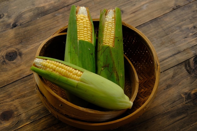 Сладкая кукуруза, также называемая сахарной кукурузой и полярной кукурузой. сырая сладкая кукуруза в плетеном бамбуковом контейнере.