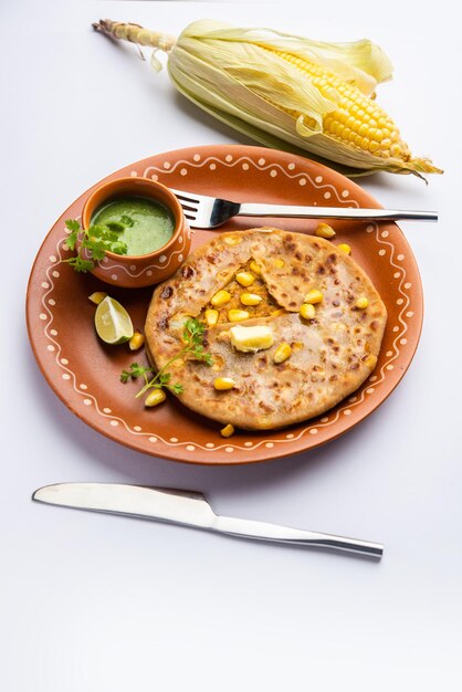 Foto paratha o parotha ripieni di mais dolce serviti in un piatto ricetta di focaccia indiana preparata con il ripieno di makai