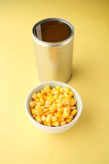 Photo sweet corns in a bowl and tin container on table