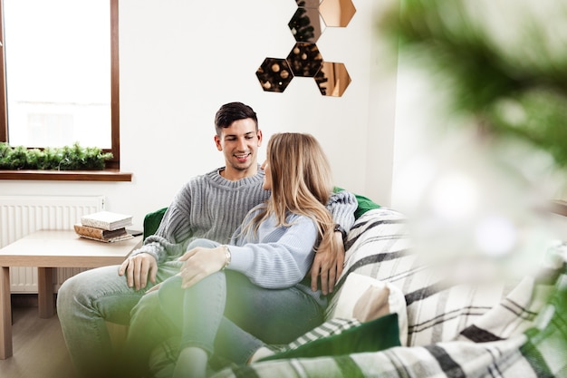 Photo sweet couple embracing on sofa at home during christmas