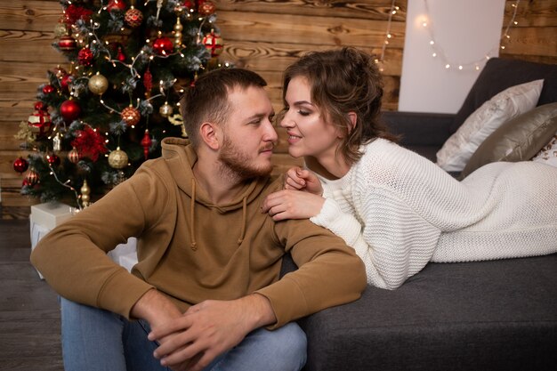 Sweet couple enjoying their time together at home. Christmas tree on background.