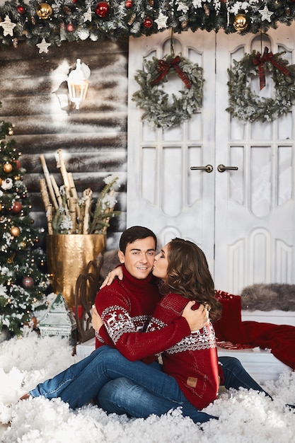 Sweet couple of lovers in christmas clothes posing in christmas decorated interior