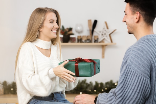 Sweet couple opening christmas gifts in the living room at home