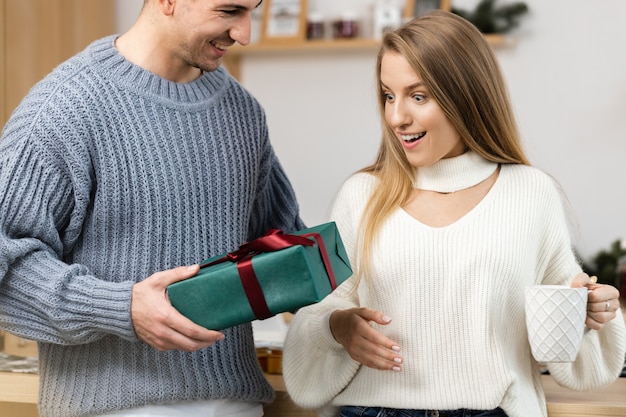 Sweet couple opening christmas gifts in the living room at home