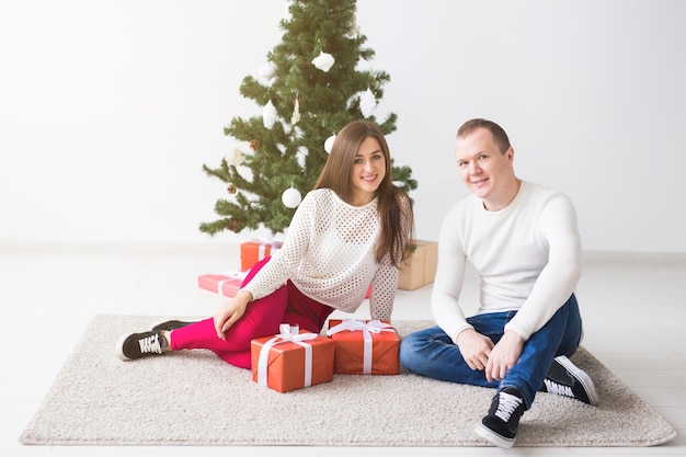 Sweet couple opening Christmas gifts, sitting in the living room.