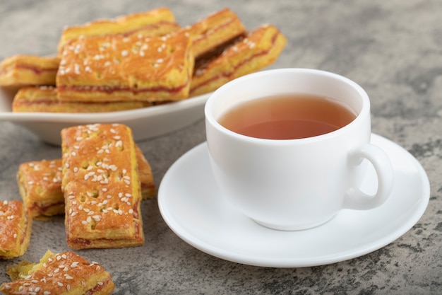 Sweet crackers with seeds and a white cup of hot tea .