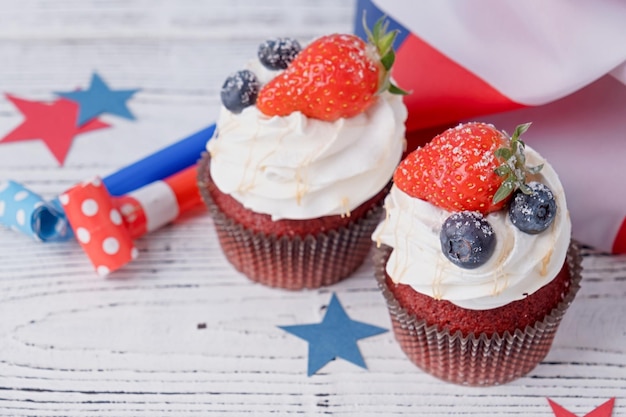 Sweet cupcakes with blueberries and strawberry usa flag on white wooden background