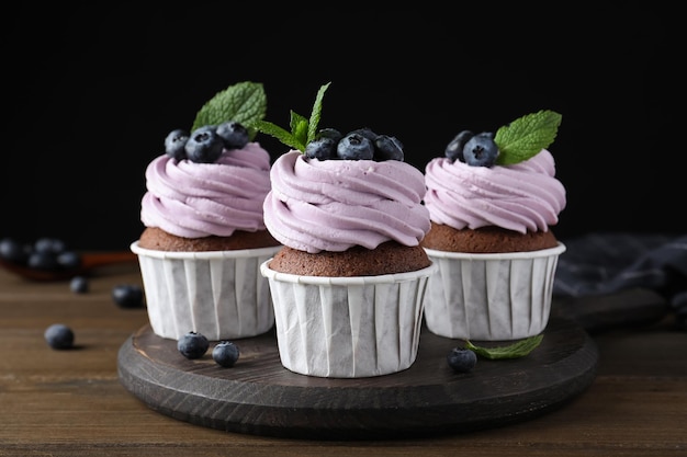 Sweet cupcakes with fresh blueberries on wooden table