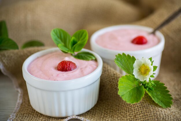 Sweet curd mass whipped with fresh strawberries in a bowl on a wooden table