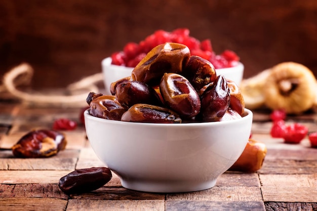 Sweet dates in bowl on wooden background selective focus