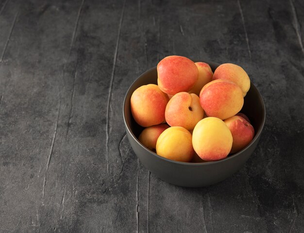 Sweet delicious apricot on dark bowl grey table summer fresh fruit