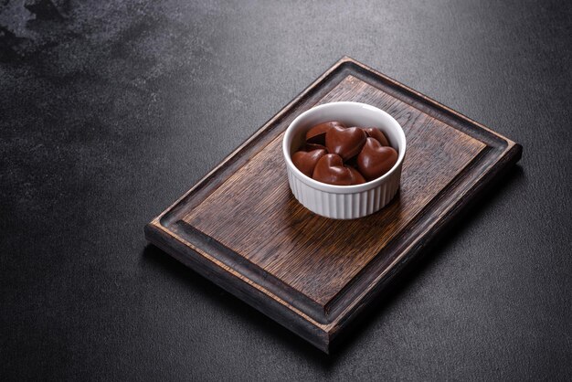 Sweet delicious sweets in the form of chocolate hearts in a white saucer