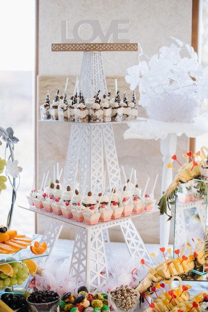 Photo sweet dessert cakes and cupcakes and jellys on the candy bar at the celebration