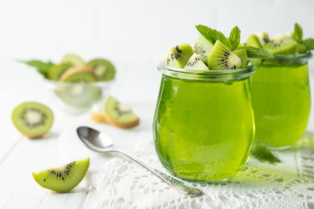 Sweet dessert jelly pudding with kiwi in glass jar on white background