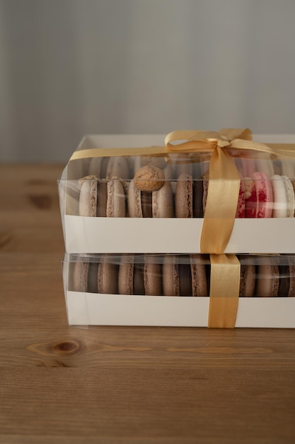 Sweet dessert macaroons in a box decorated with a ribbon on a wooden table