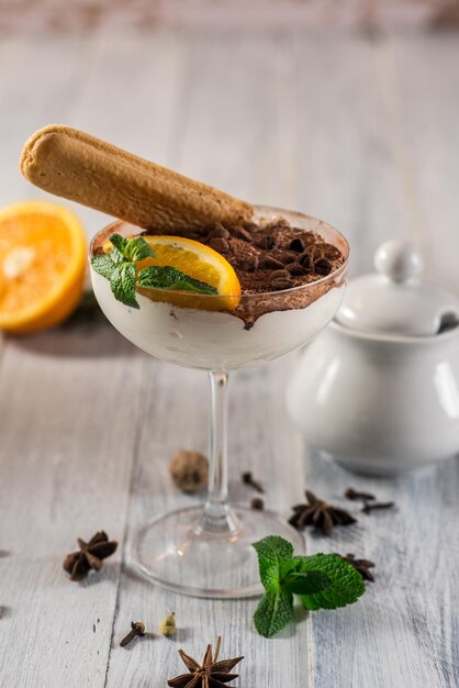 Sweet dessert tiramisu in glass on the white wooden background