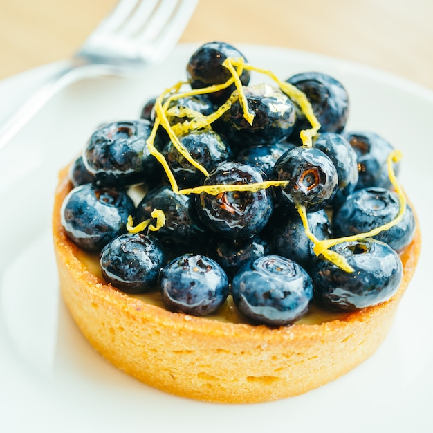 Sweet dessert with blueberry tart in white plate