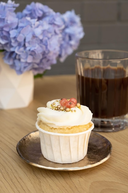 Sweet dessert with cream and coffee on wooden cafe table with flowers