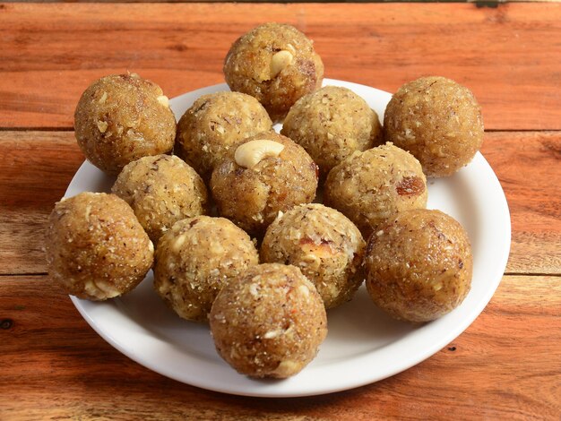 Sweet Dink laddu ook bekend als Dinkache ladoo of gond ke laddoo gemaakt met behulp van eetbare kauwgom met droge vruchten geserveerd op een witte plaat op een rustieke houten achtergrond selectieve aandacht