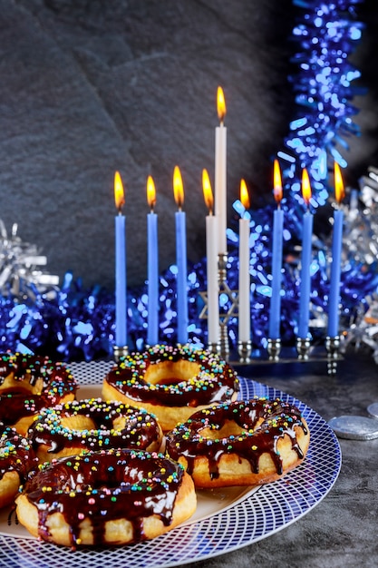 Sweet donuts and menorah with burning candles