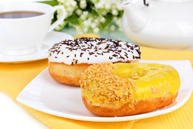 Sweet donuts with cup of tea on table closeup