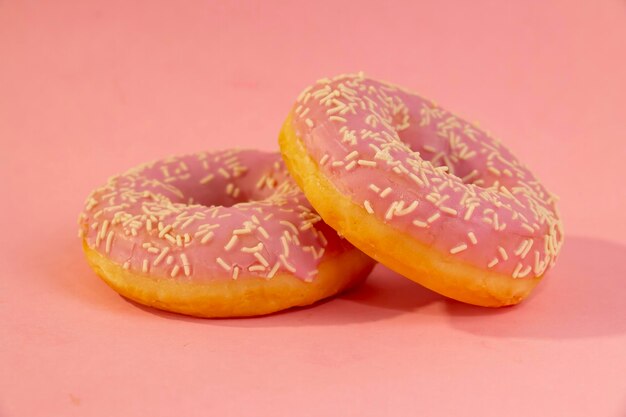 Photo sweet donuts with sprinkles on a pink background sugar calories homemade sweets concept