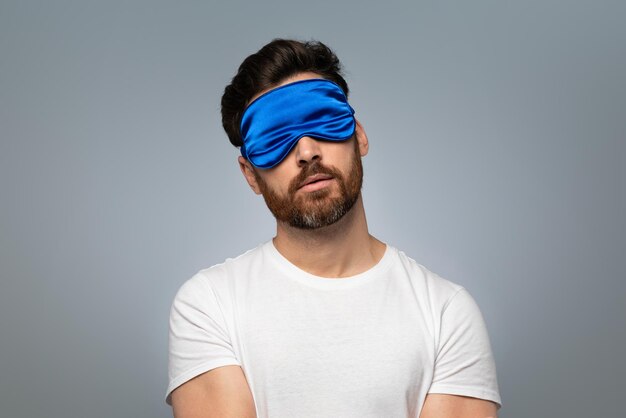 Sweet dreams concept Asleep middle aged bearded man in sleep mask standing over grey background with closed eyes