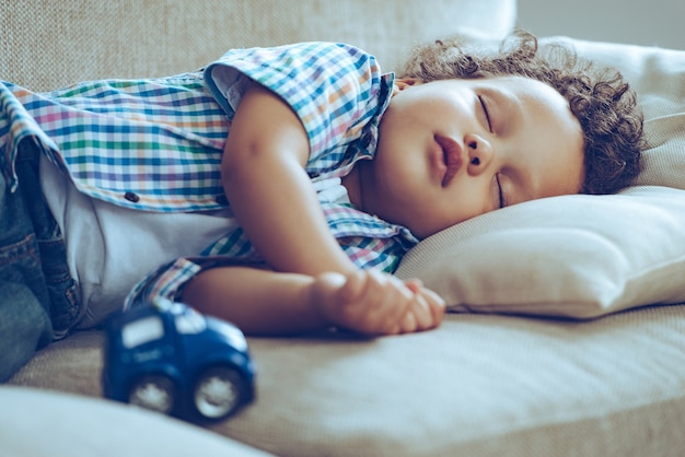 Sweet dreams. little african baby boy sleeping while lying on couch at home