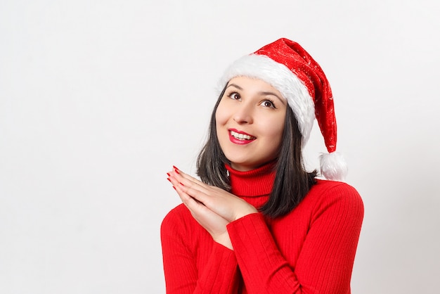 Dolce giovane donna sognante in un maglione rosso e cappello di natale