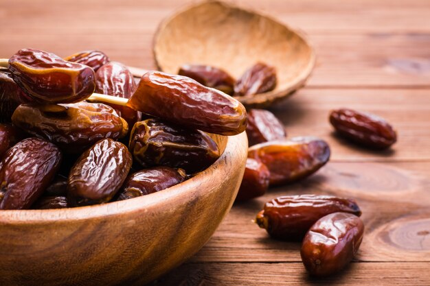 Sweet dried dates fruit in a wood bowl and on the table. 