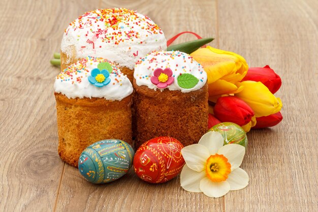 Sweet Easter cakes painted Easter eggs red and yellow tulips narcissus on wooden background