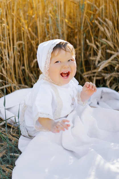 Sweet eightmonthold baby boy sitting on a blanket in a field and laughing