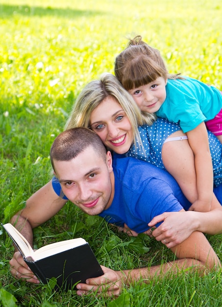 Милая семья читает книгу на зеленой траве