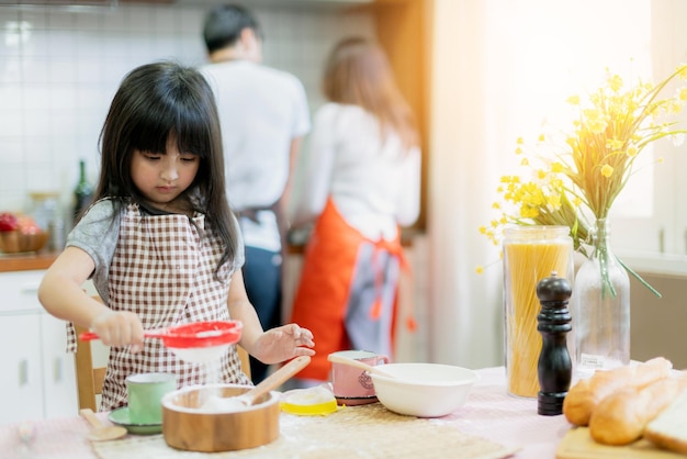 Dolci attività del fine settimana in famiglia che cucinano insieme a papà, mamma e figlia, momento di felicità e gioioso hobby di cucina domestica