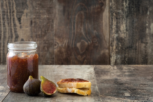 Sweet fig jam in jar on wooden table copy space