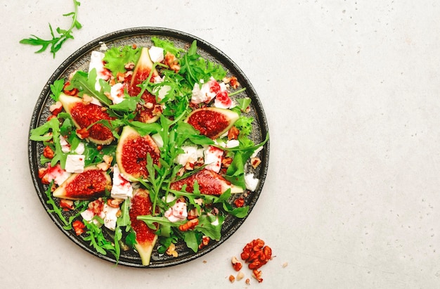 Sweet fig salad with soft goat cheese walnuts arugula and jam dressing on white background top view copy space