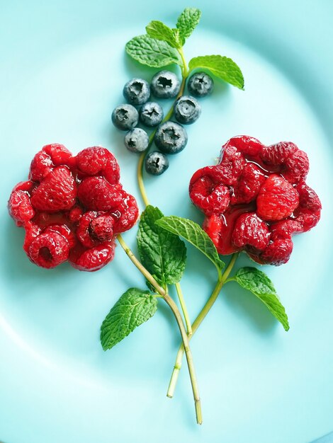 Foto dolci fiori a base di mirtillo e lampone su sfondo blu