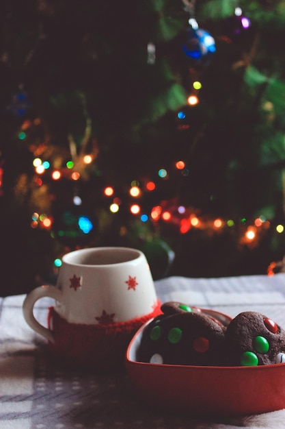 照らされたクリスマスツリーに照らされたテーブルの上にある甘い食べ物