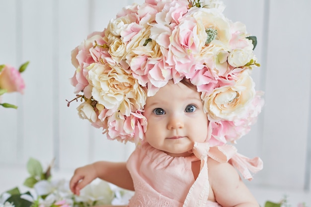 Sweet funny baby in hat with flowers. Easter. Cute baby girl 6 months wearing flower hat.