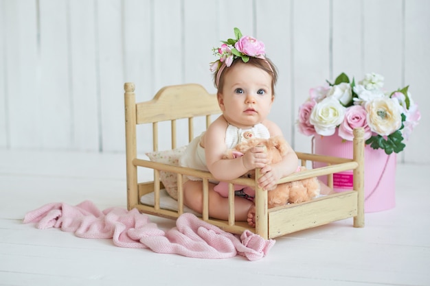 Sweet funny baby in hat with flowers. EasterCute baby girl 6 months wearing flower hat.